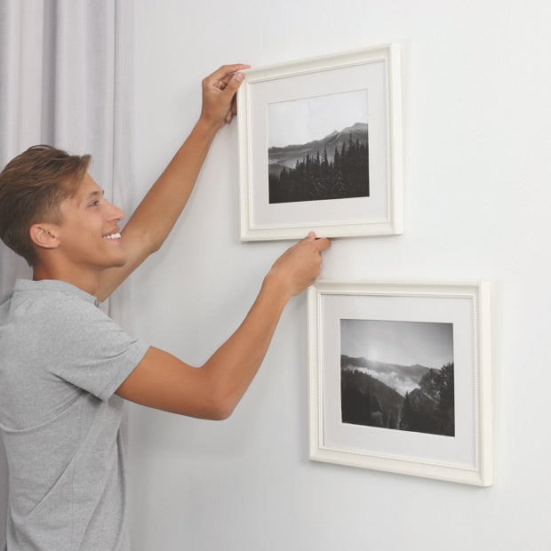 Junge hängt Bilder an die Wand